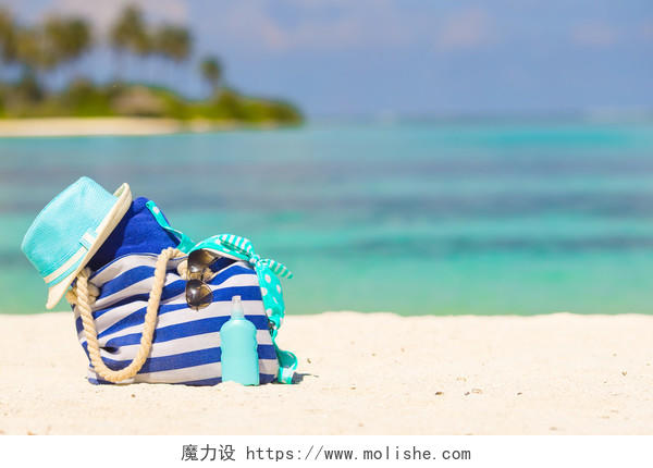 蓝色的袋子、 草帽、 拖鞋和毛巾洁白的沙滩上